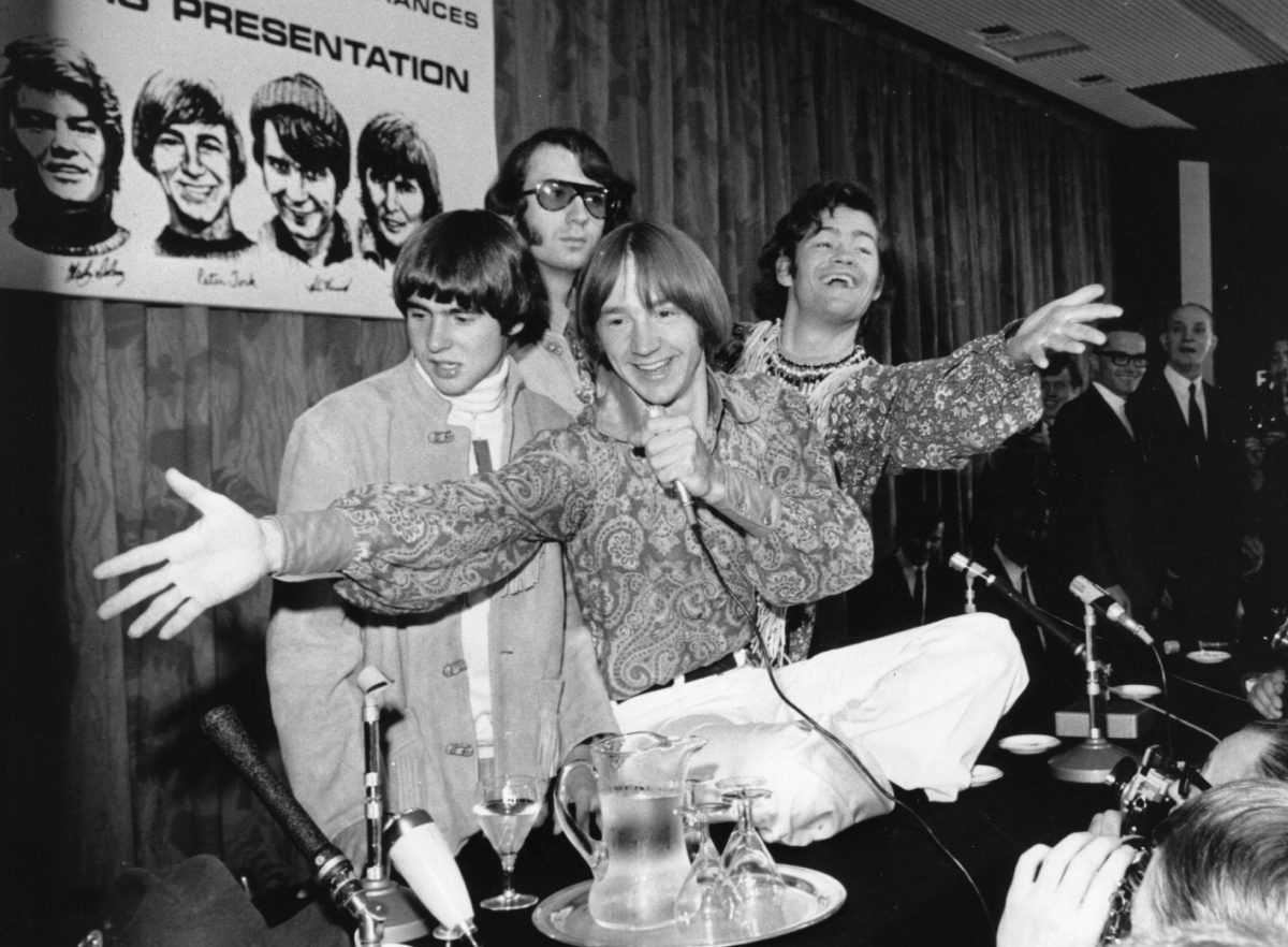 Davy Jones, Mike Nesmith, Peter Tork et Micky Dolenz des Monkees près d'une affiche