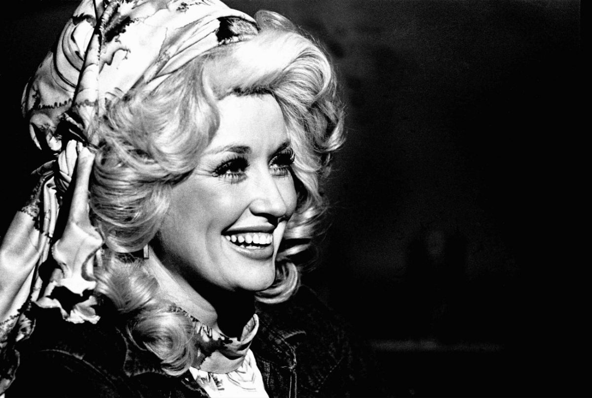 Une photo en noir et blanc de Dolly Parton portant un foulard en soie autour de ses cheveux.