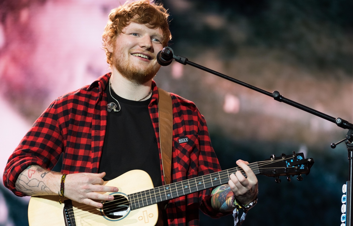 Ed Sheeran jouant de sa guitare et voyant sur scène.