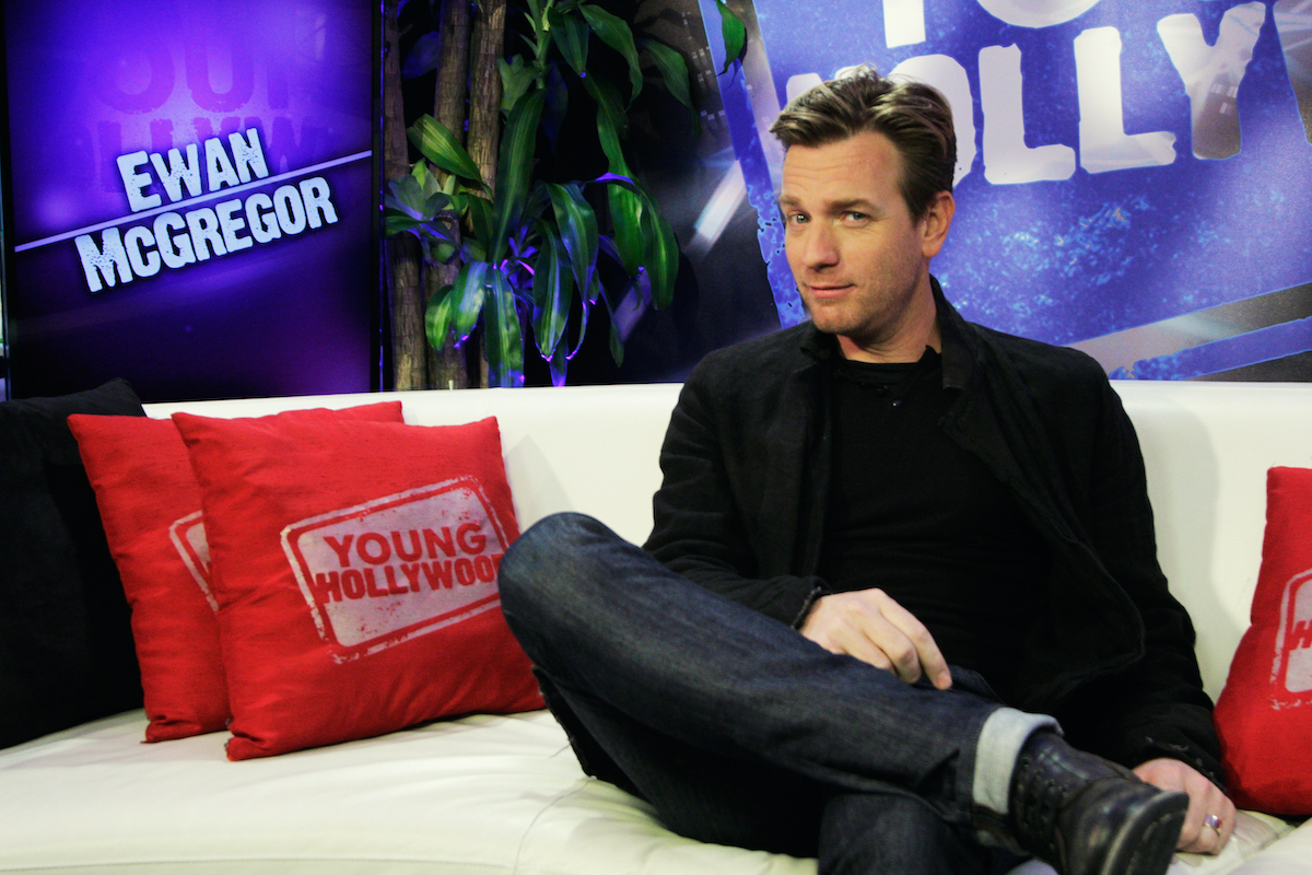 Ewan McGregor sourit et regarde la caméra assis sur un canapé blanc
