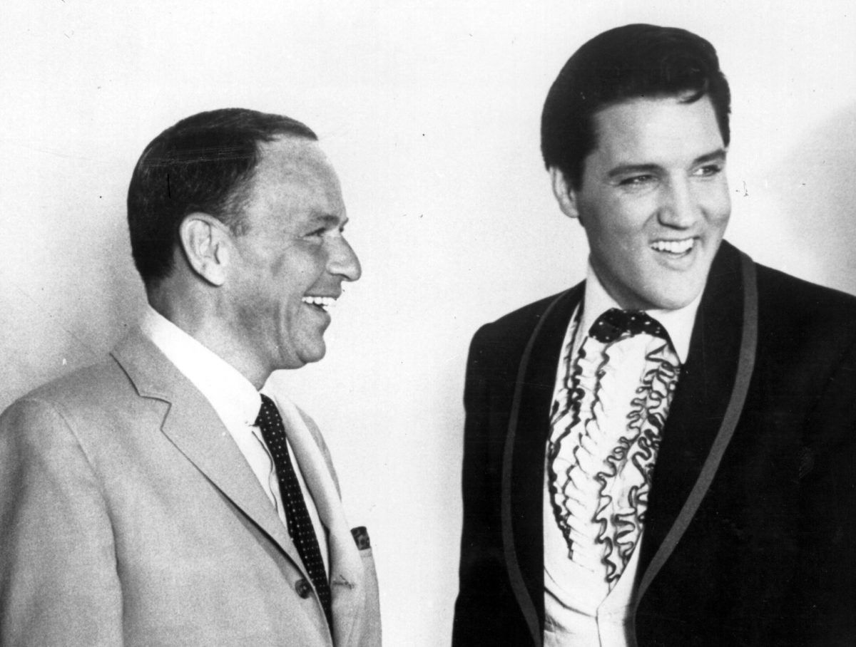Une photo en noir et blanc de Frank Sinatra et Elvis portant des costumes et souriant.