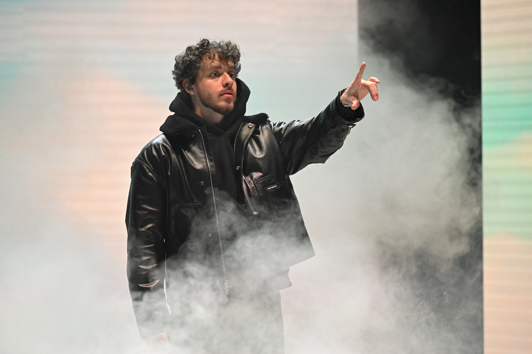 Jack Harlow portant une veste en cuir noire et pointant du doigt