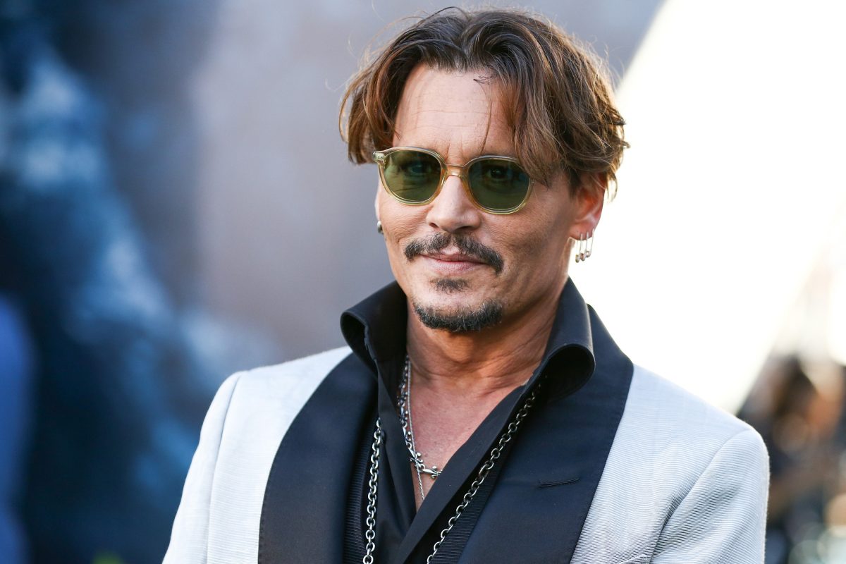 Johnny Depp pose lors d'un événement tout en portant une veste noire et blanche. 