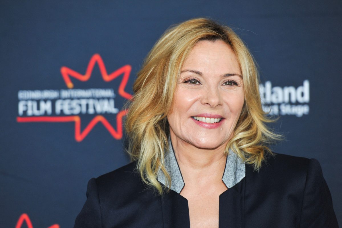 La star de 'Porky's Kim Cattrall souriant dans une veste noire devant un festival du film étape et répétition