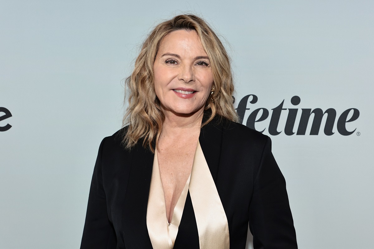 Kim Cattrall sourit en portant une robe noire.
