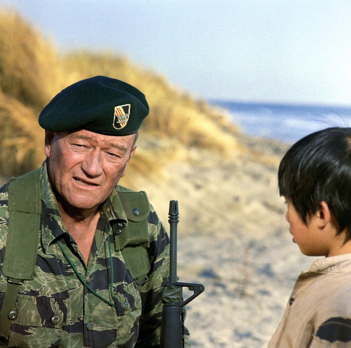 John Wayne dans le rôle du colonel Mike Kirby dans 'The Green Berets' dans un uniforme militaire tenant une arme à feu