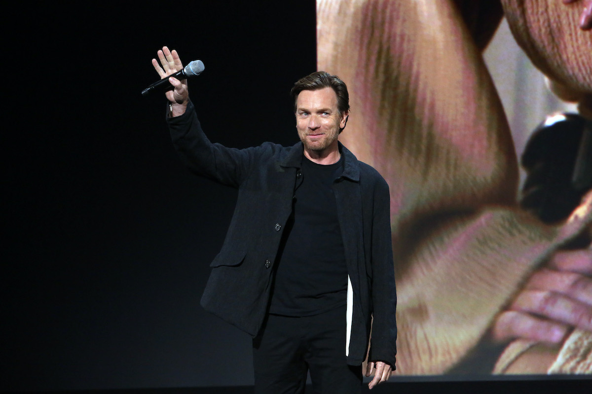 Ewan McGregor vêtu de noir sourit sur scène et salue