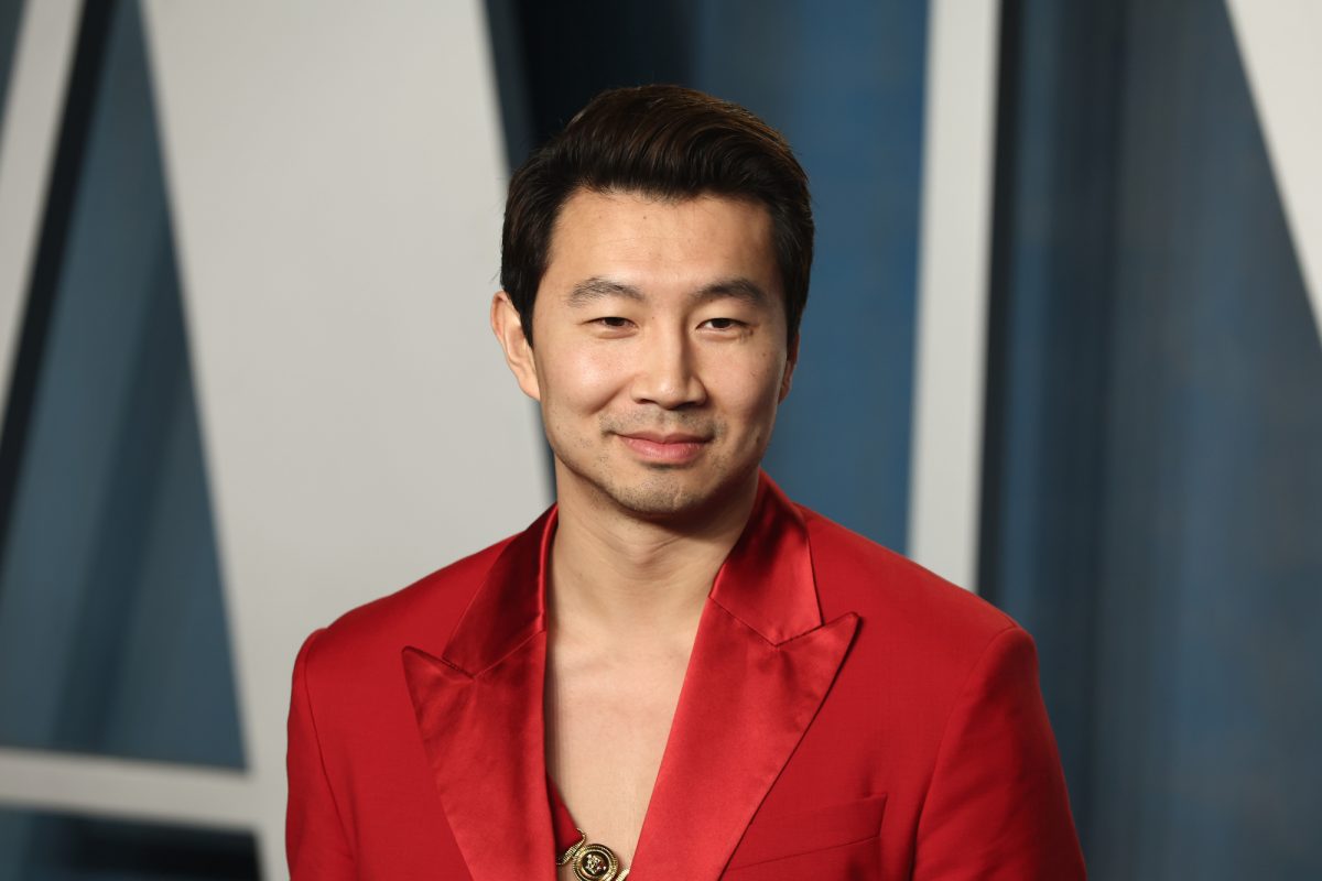L'acteur de 'Barbie' Simu Liu portant un costume rouge avec un léger sourire