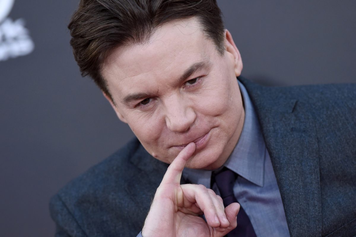 Mike Myers, star potentielle d'Austin Powers 4, tient son petit doigt contre ses lèvres et porte un costume