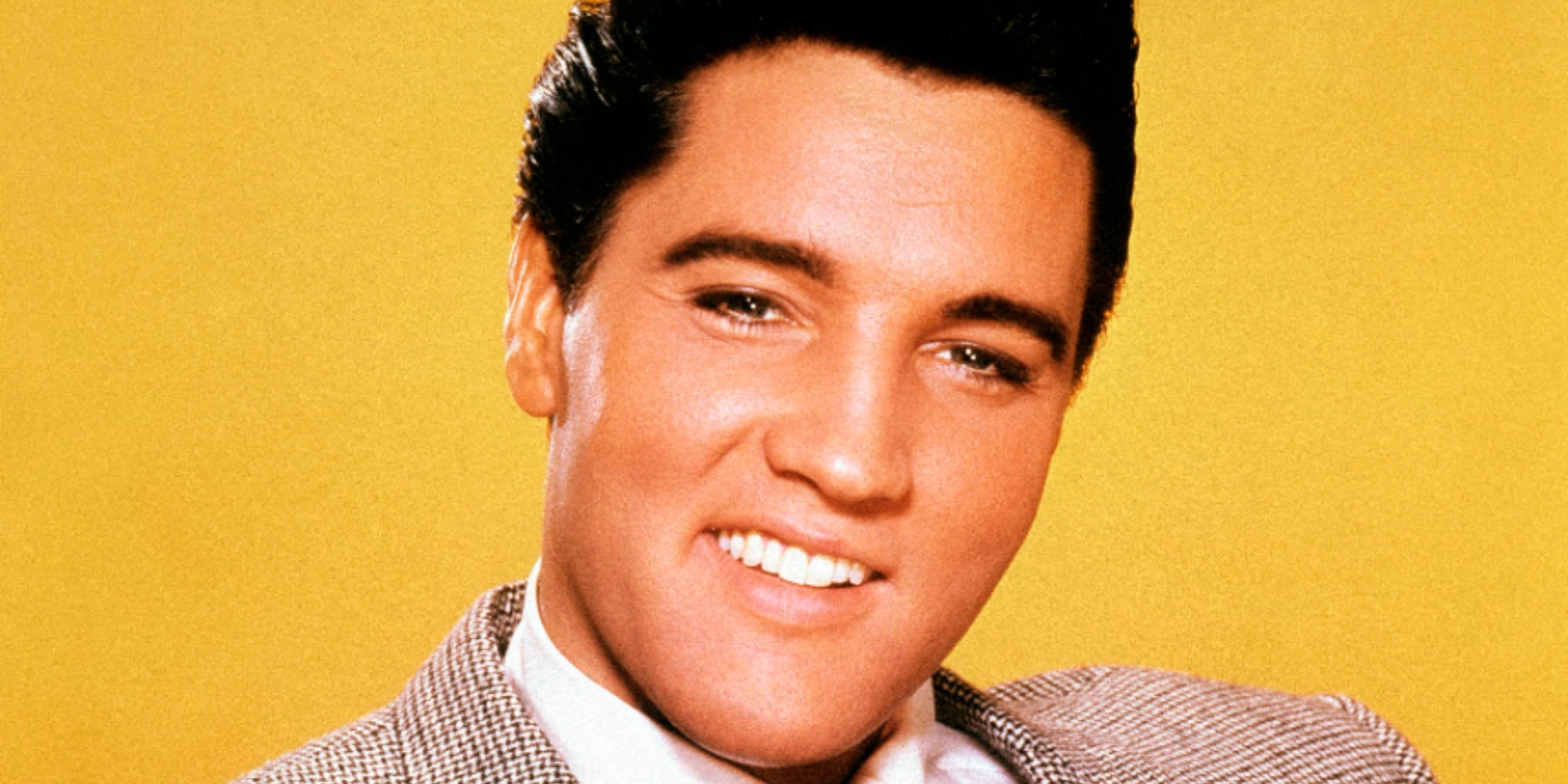 Elvis Presley dans une photographie de presse avec un fond jaune vif.