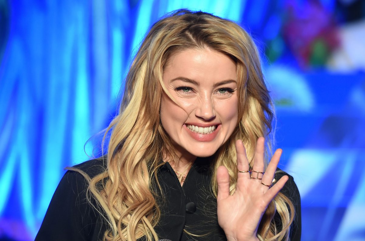 La star d'Aquaman, Amber Heard, lève la main en agitant et en souriant