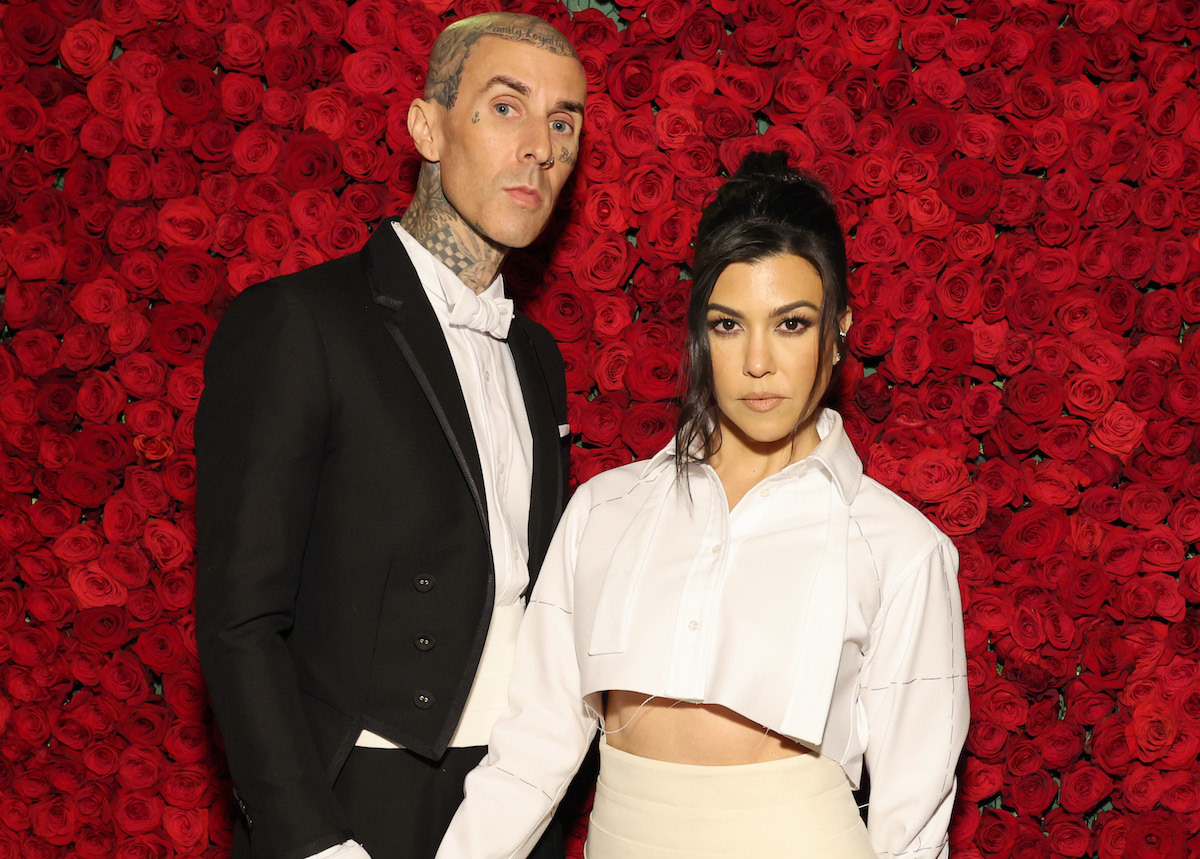 Travis Barker et Kourtney Kardashian devant un fond rouge