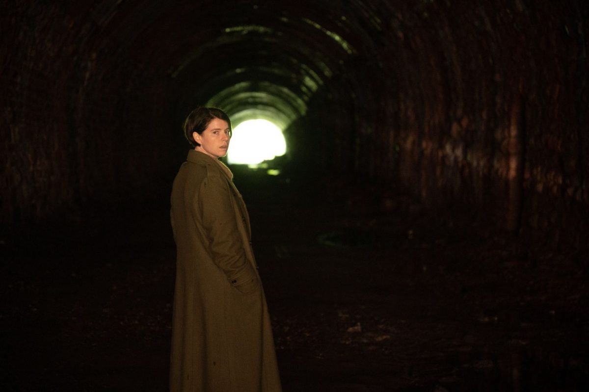 Jessie Buckley dans le rôle de Harper dans 'Men', un film A24 sur la masculinité toxique debout dans un tunnel regardant par-dessus son épaule