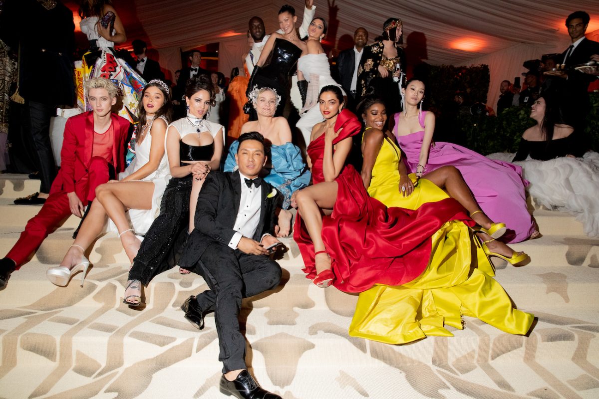 Des participants en tenues colorées assis sur les marches du Met Gala 2018