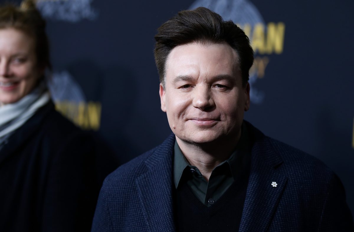 La star de 'Shrek' Mike Myers portant une veste et une chemise à col devant un step and repeat