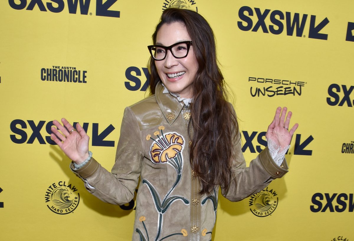 'Minions: The Rise of Gru' acteur Michelle Yeoh debout devant une étape jaune du Festival du film SXSW et répétez en tenant ses mains tendues