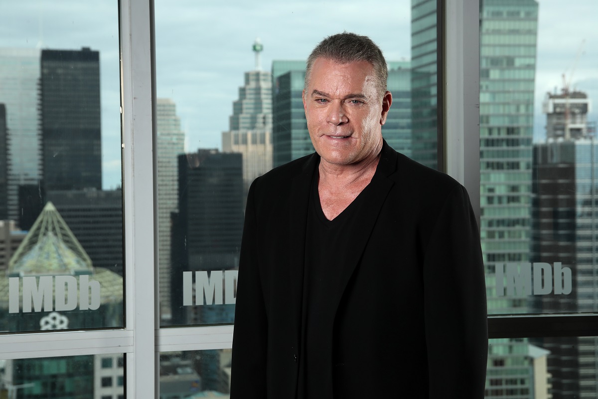 Ray Liotta souriant tout en portant un costume tout noir.