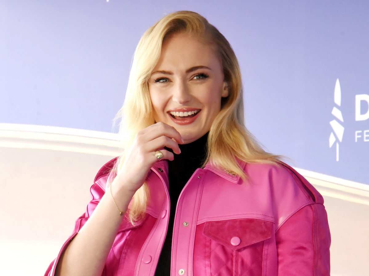 Sophie Turner portant une veste rose et souriant