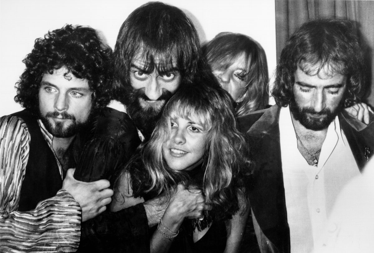 Une photo en noir et blanc de Lindsey Buckingham, Mick Fleetwood, Stevie Nicks, Christine McVie et John McVie de Fleetwood Mac posant ensemble.