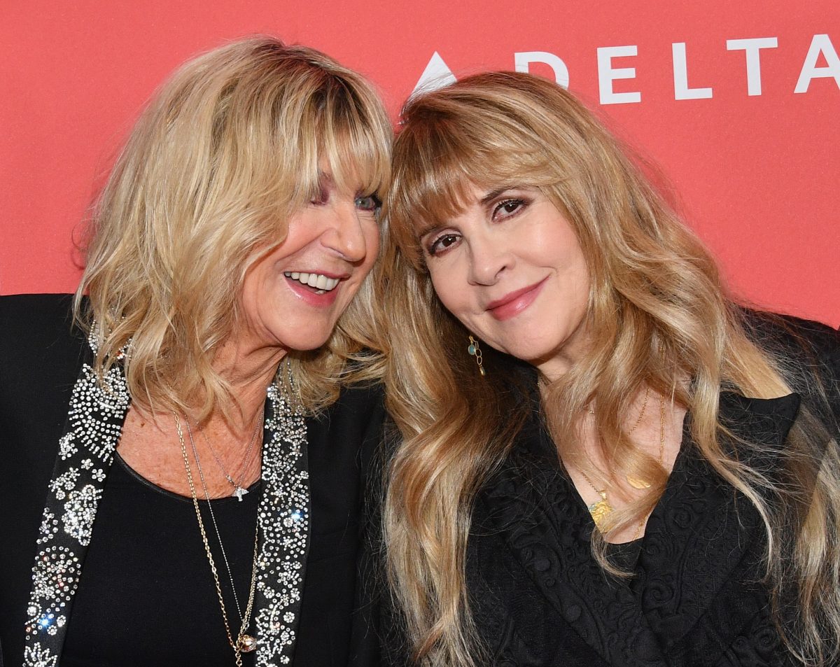 Christine McVie et Stevie Nicks portent du noir et se tiennent sur un fond rouge.