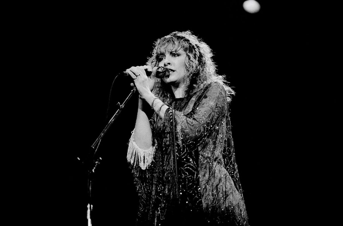 Une photo en noir et blanc de Stevie Nicks debout sur scène et tenant un microphone.
