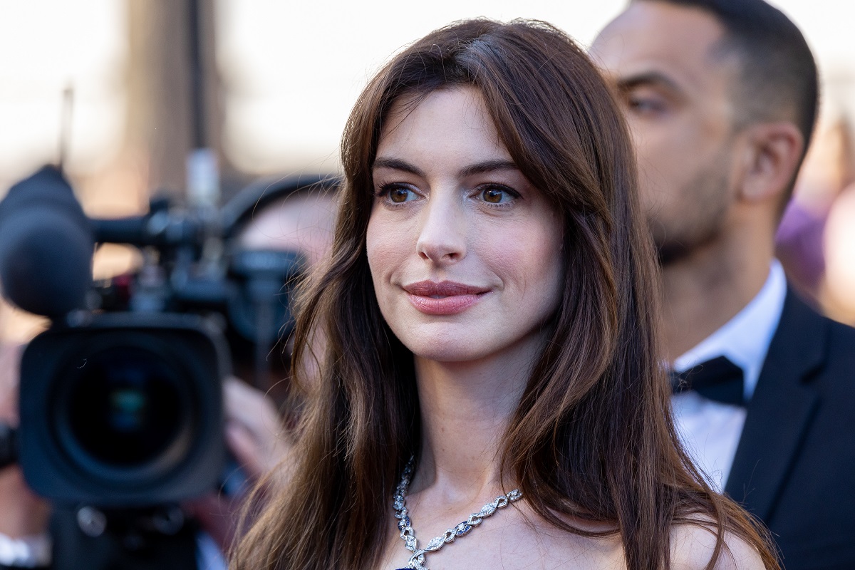Anne Hathaway souriante en portant une robe blanche.