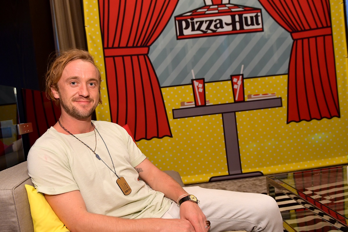 Tom Felton souriant tout en portant un t-shirt blanc.