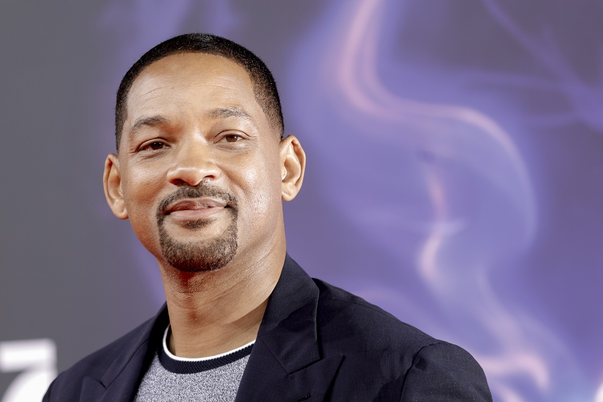 Will Smith sourit en portant une chemise grise et un blazer.
