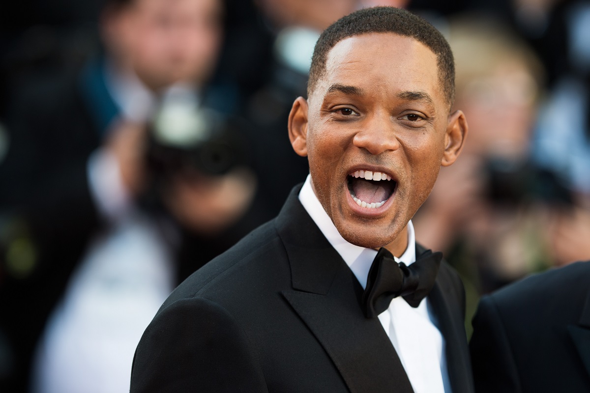 Will Smith sourit tout en étant rasé de près et portant un costume.