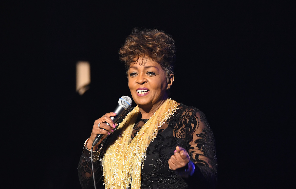 Anita Baker, qui a obtenu son master grâce à Chance the Rapper, portant une écharpe dorée et tenant un micro