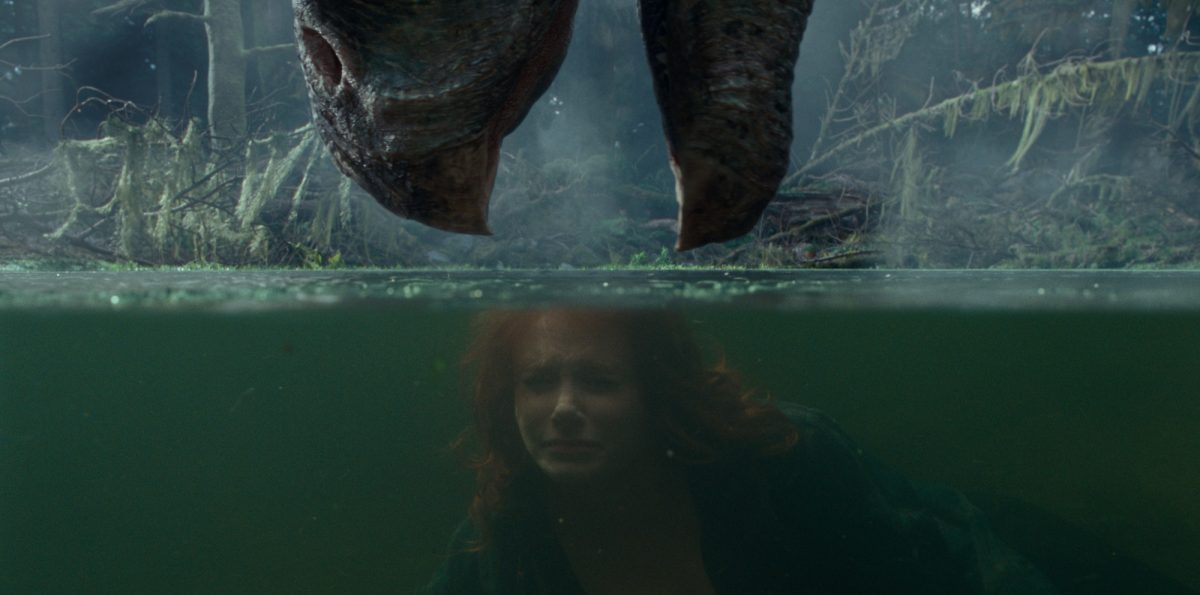 'Jurassic World Dominion' Therizinosaurus et Bryce Dallas Howard dans le rôle de Claire Dearing.  Le Therizinosaurus abaisse sa bouche vers l'eau avec Howard retenant son souffle sous l'eau.