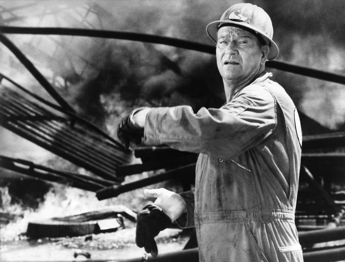 John Wayne, qui a fait rage face aux critiques négatives des critiques de cinéma. Il porte un casque et agite la main.