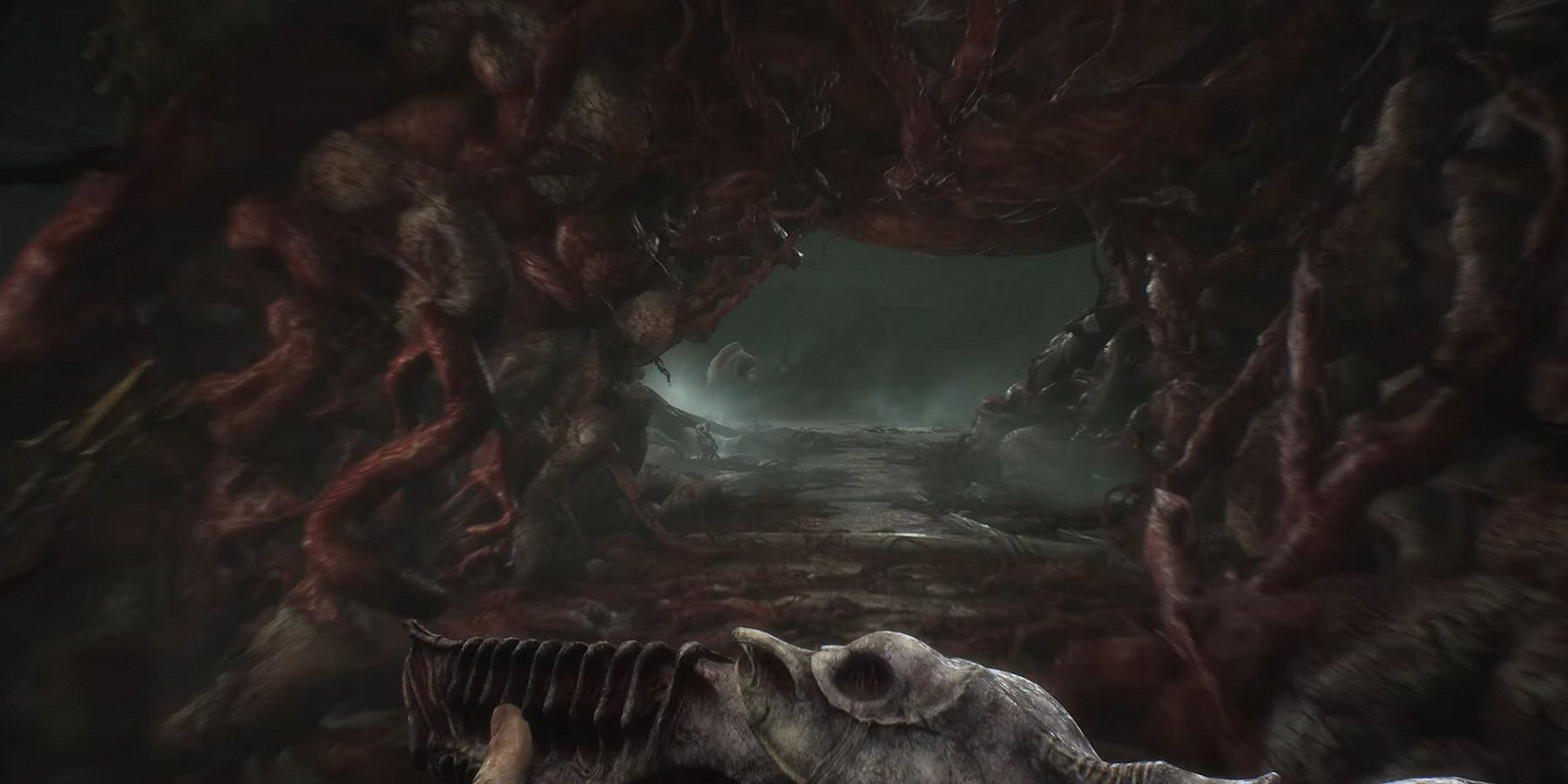 Une image de Scorn montrant le joueur tenant une arme alors qu'il entre dans un tunnel d'horreur corporelle.
