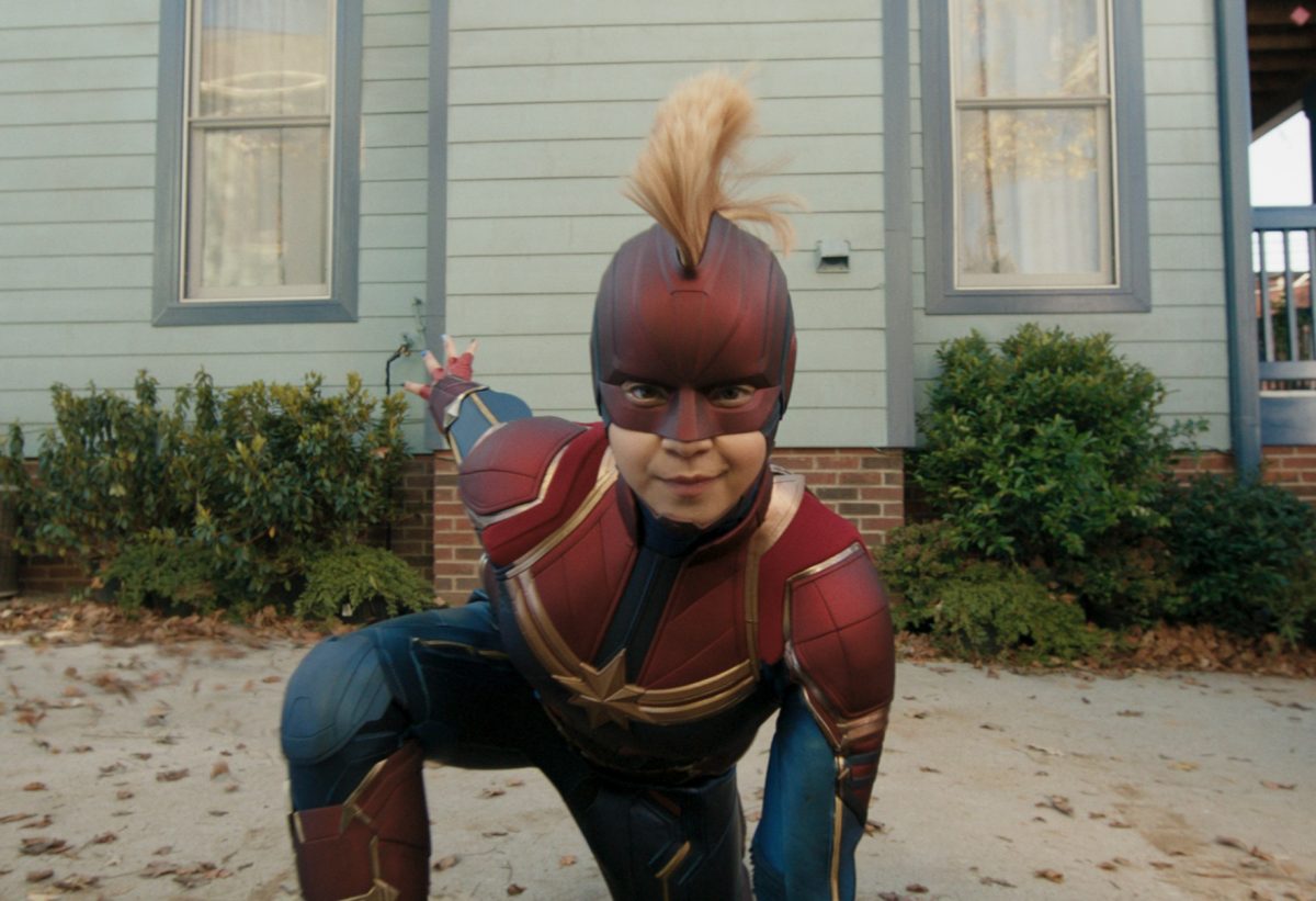 Iman Vellani dans le rôle de Kamala Khan dans 'Ms. Marvel », dont la date de sortie de l'épisode 2 est le 15 juin. Elle porte un costume de capitaine Marvel et elle fait une pose de super-héros agenouillée devant sa maison.