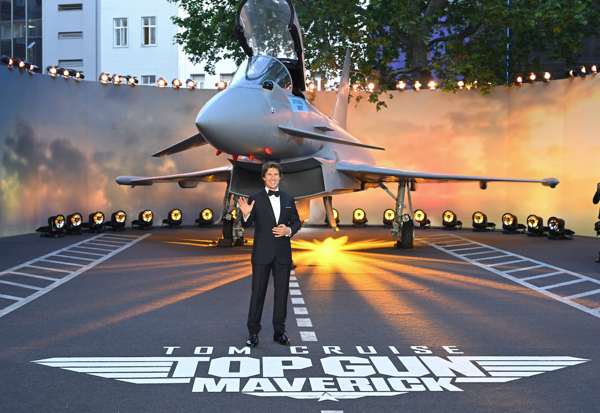 Tom Cruise salue devant un avion à la première du film Top Gun: Maverick.