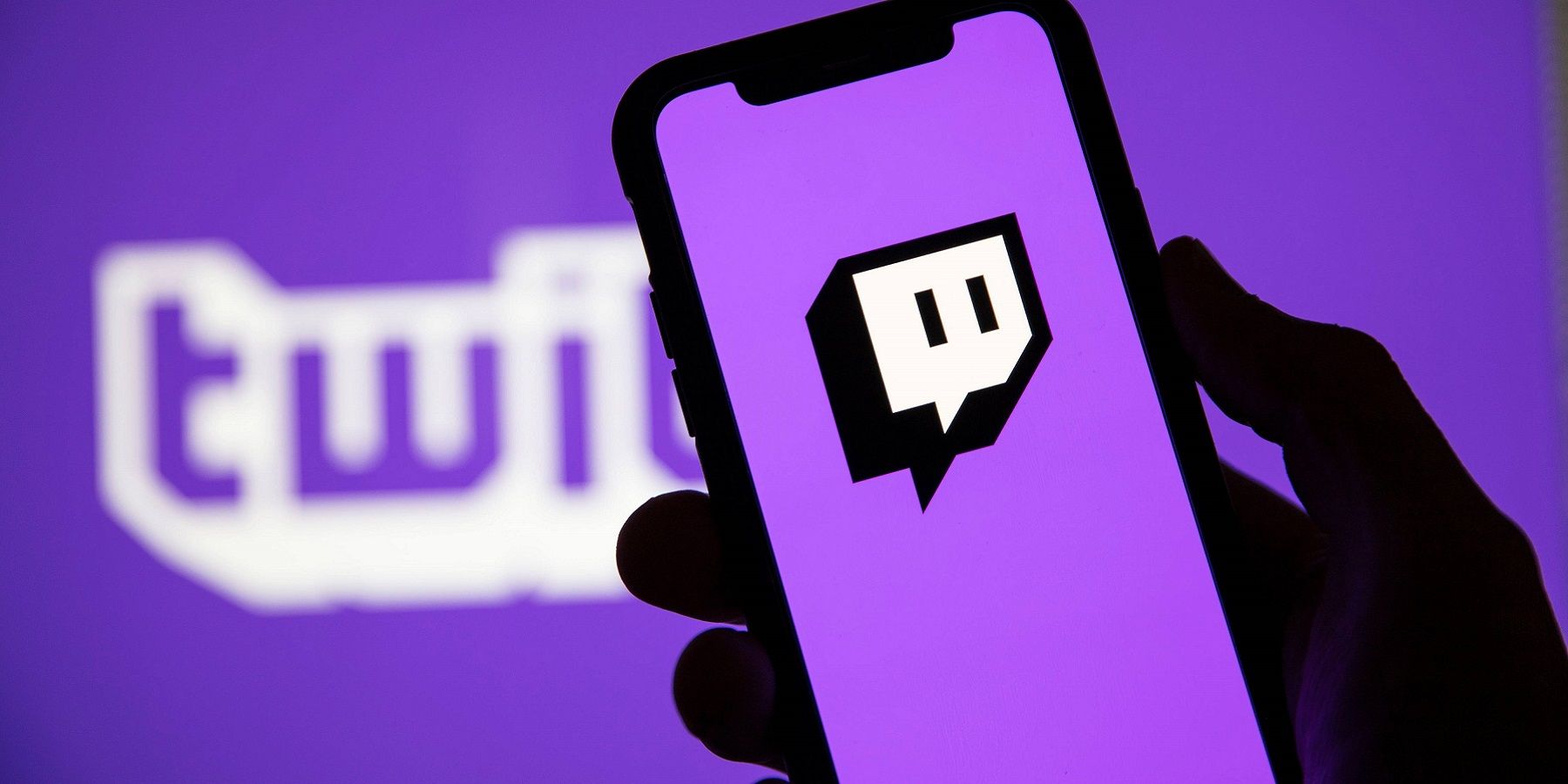 Un han tenant un téléphone avec le logo twitch à l'écran, le tout sur un fond violet.