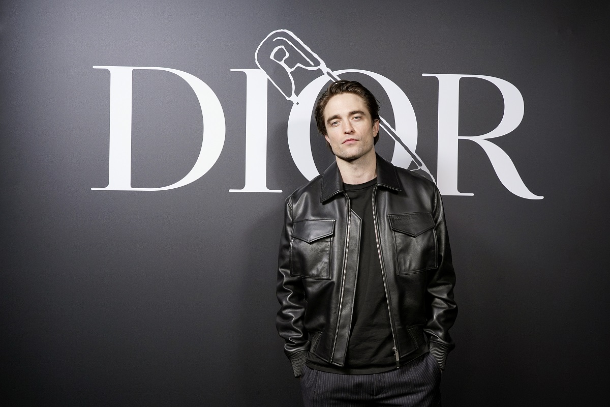 Robert Pattinson posant en portant une veste en cuir noire.