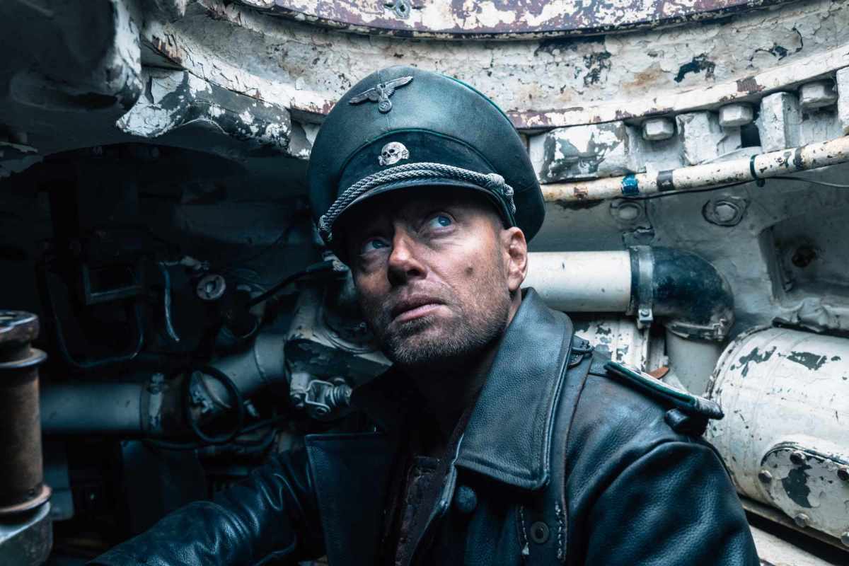 'Sisu' Aksel Hennie dans le rôle de l'Obersturmführer Bruno Helldorf portant un uniforme nazi à l'intérieur d'un char, regardant vers le trou.
