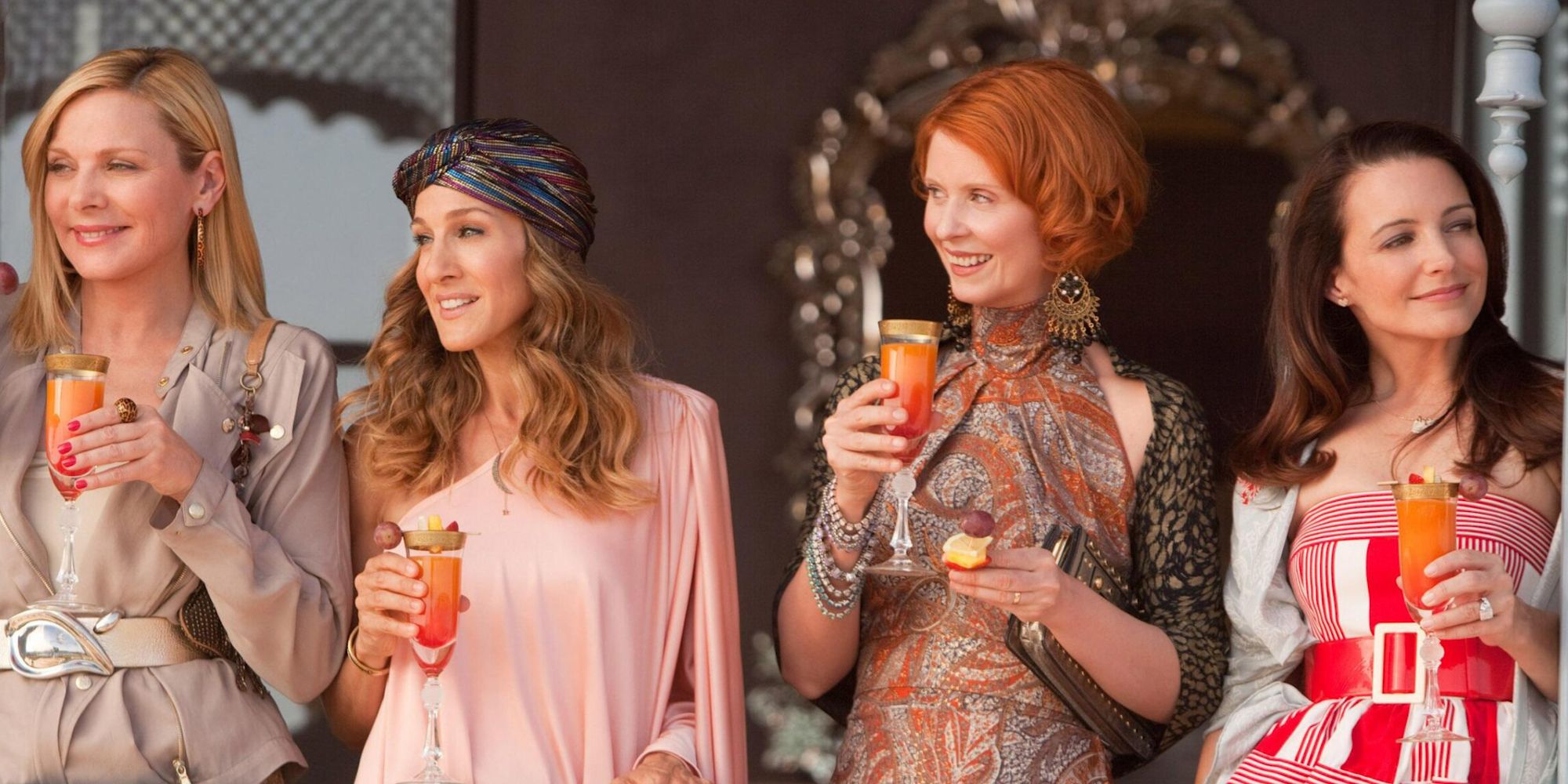 Le casting de Sex and the City 2 tenant des coupes de champagne et souriant.