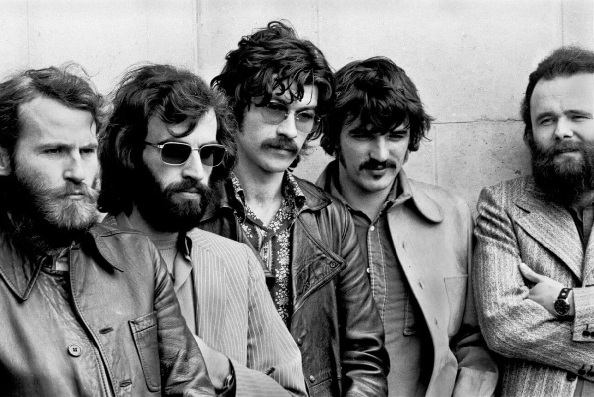 Une photo en noir et blanc de Levon Helm, Richard Manuel, Robbie Robertson, Rick Danko et Garth Hudson de The Band posant contre un mur.