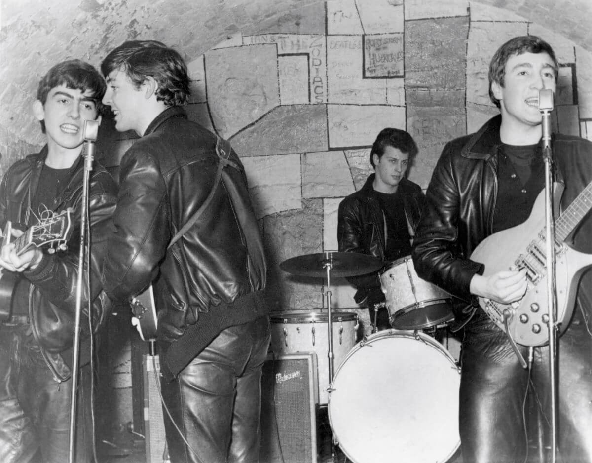 Une photo en noir et blanc des Beatles jouant un concert avec Pete Best comme batteur.