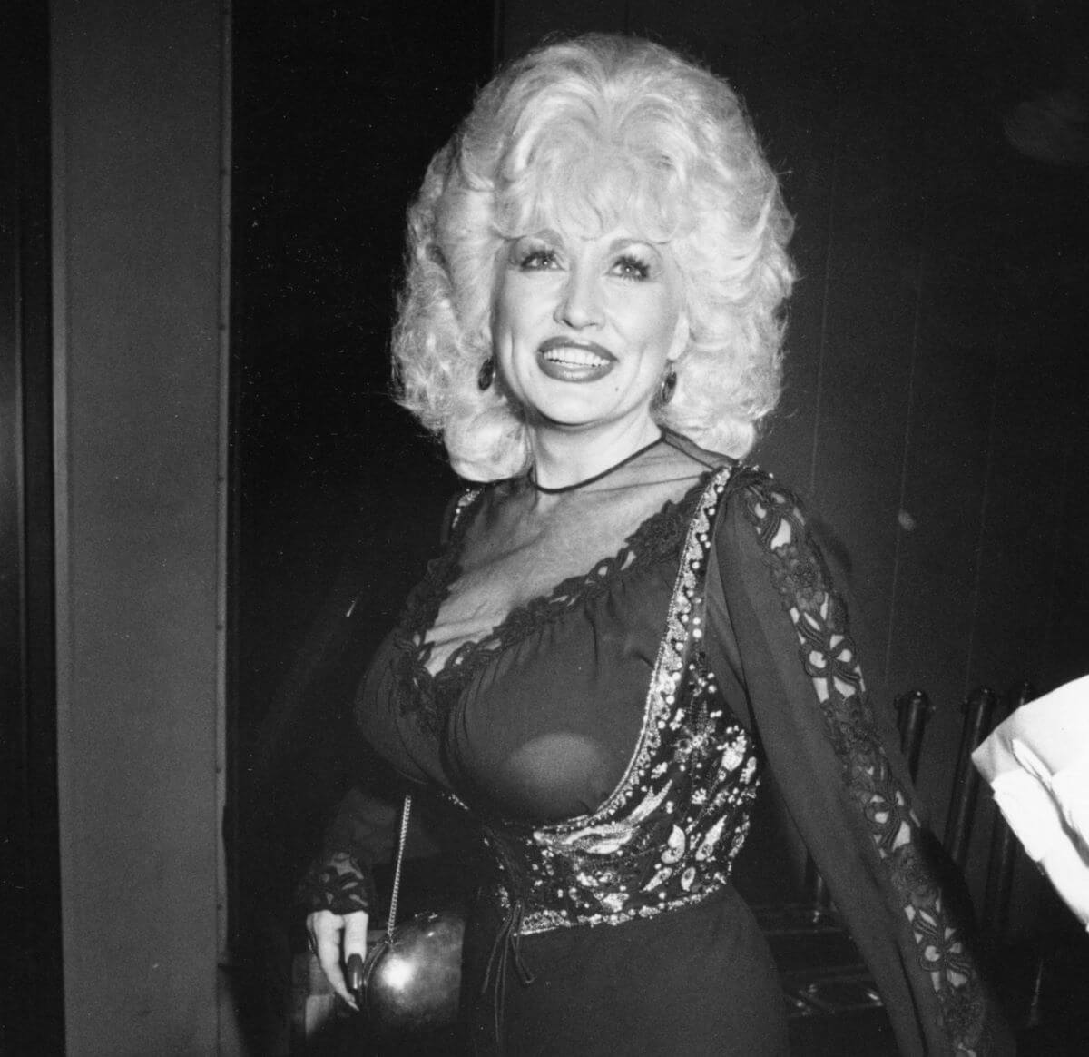 Une photo en noir et blanc de Dolly Parton portant une robe à décolleté transparent.