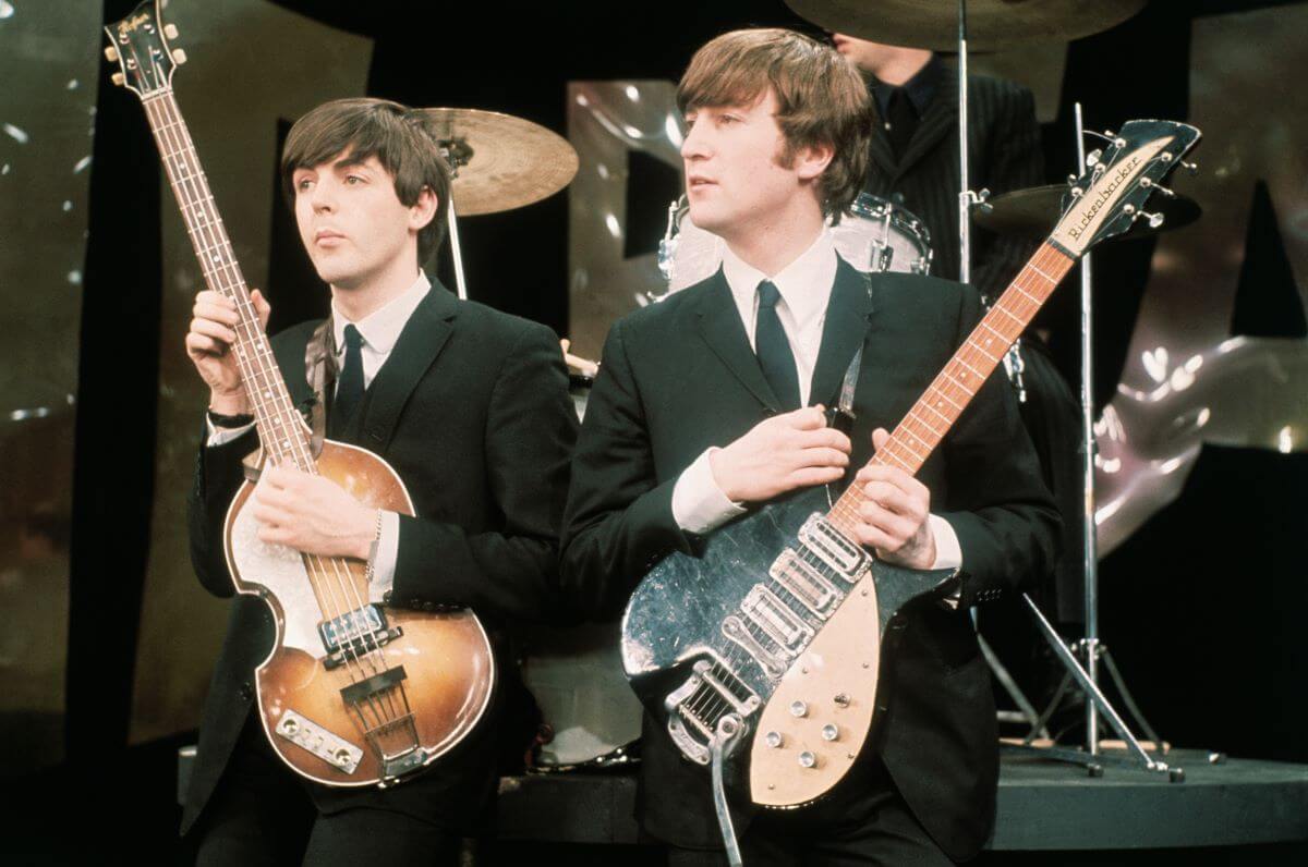 Paul McCartney et John Lennon portent des costumes et tiennent des guitares.