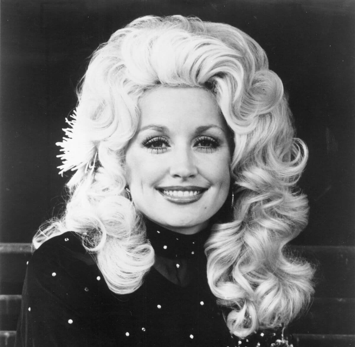 Une photo en noir et blanc de Dolly Parton portant un col roulé et souriante.