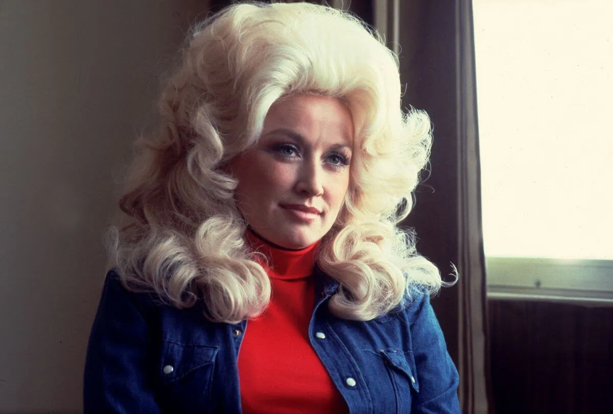 Dolly Parton porte un col roulé rouge et une chemise en jean.