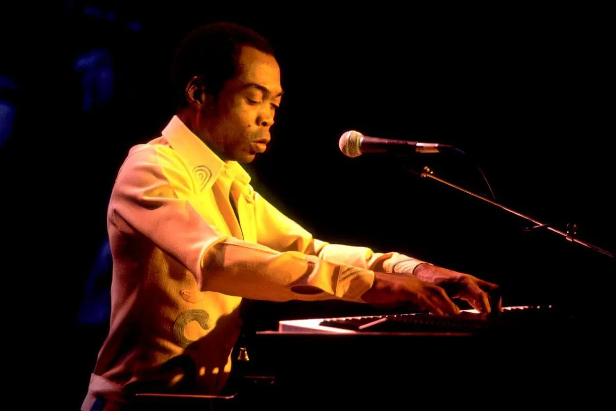 Fela Kuti porte une chemise blanche et joue du piano.