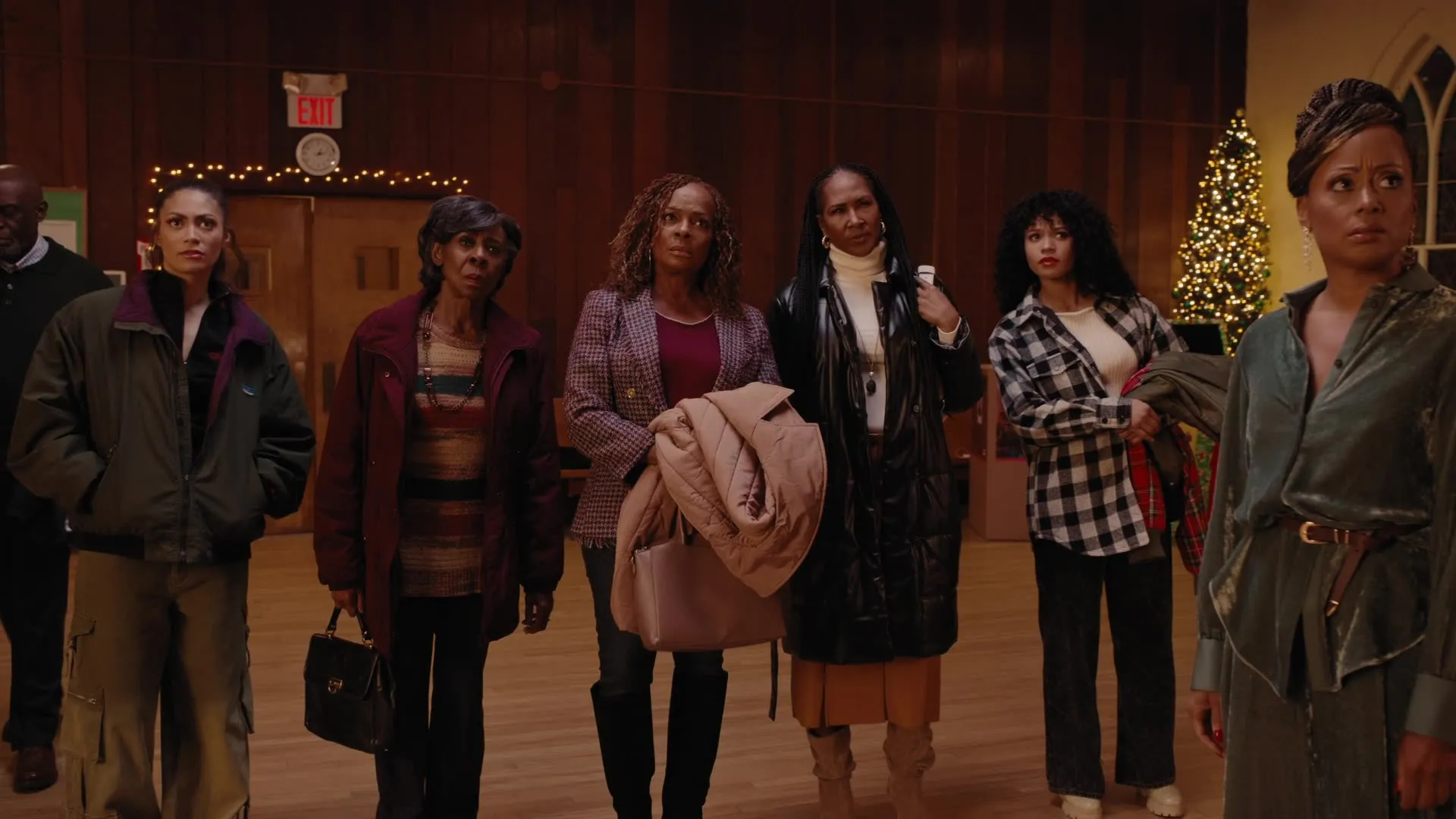 Groupe de personnes debout devant les décorations de Noël dans « Reines de Noël »