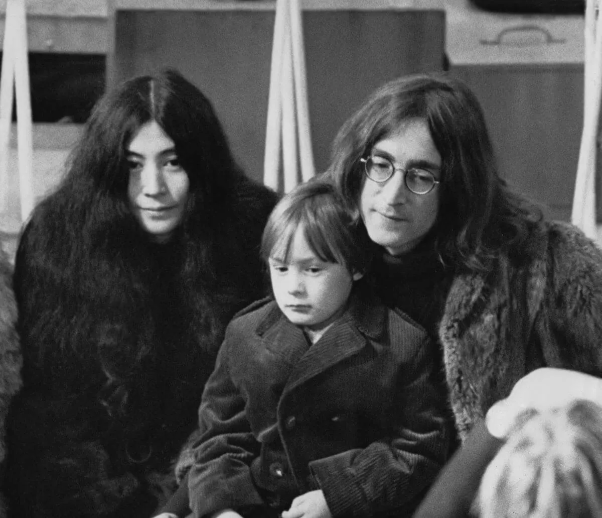 Une photo en noir et blanc de Yoko Ono, Julian Lennon et John Lennon assis ensemble.