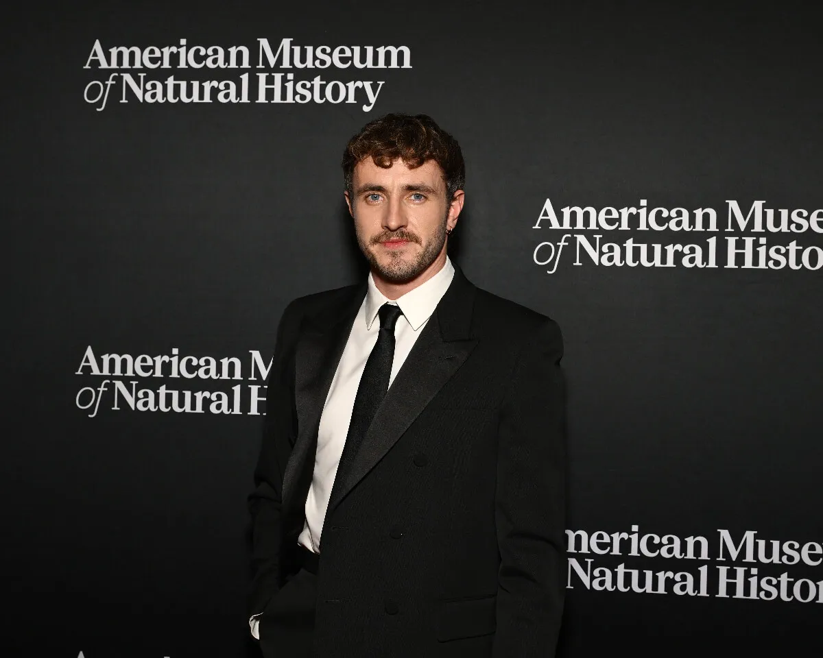 Paul Mescal porte un costume et se tient devant les panneaux indiquant le Musée américain d'histoire naturelle.