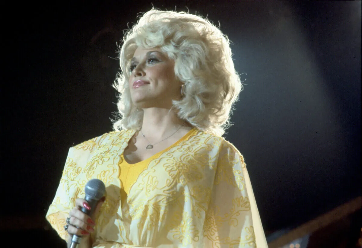 Dolly Parton porte du jaune et tient un microphone.
